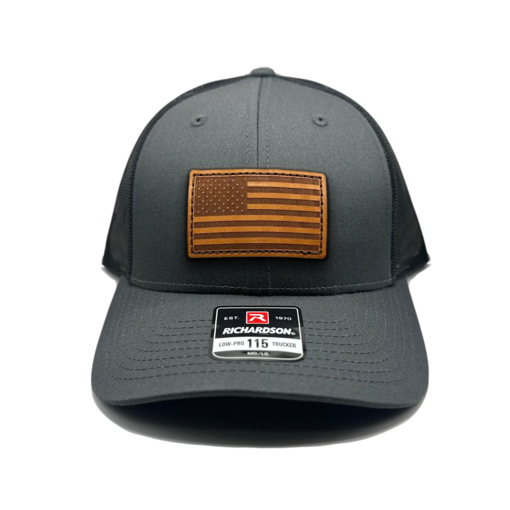 Charcoal/Black American Flag Hat by Richardson 115 with a genuine leather American Flag patch, laser-engraved and hand-sewn, on a charcoal and black trucker hat.