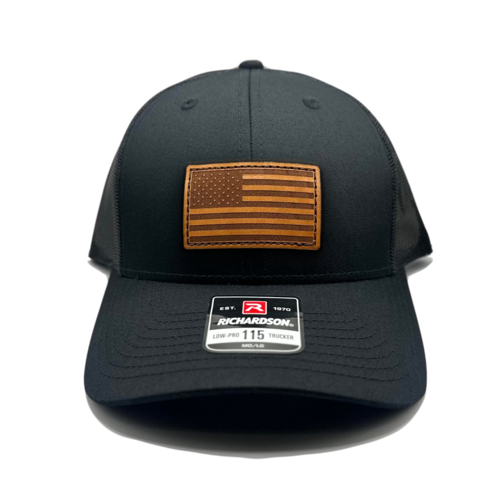 Black Richardson 115 hat featuring a distinctive American flag patch crafted from genuine leather. This unique patch is laser engraved and securely sewn onto the hat. The Richardson 115 is a low profile trucker style hat, adjustable to fit small or M/L sizes, making it a versatile and fashionable accessory for any occasion.