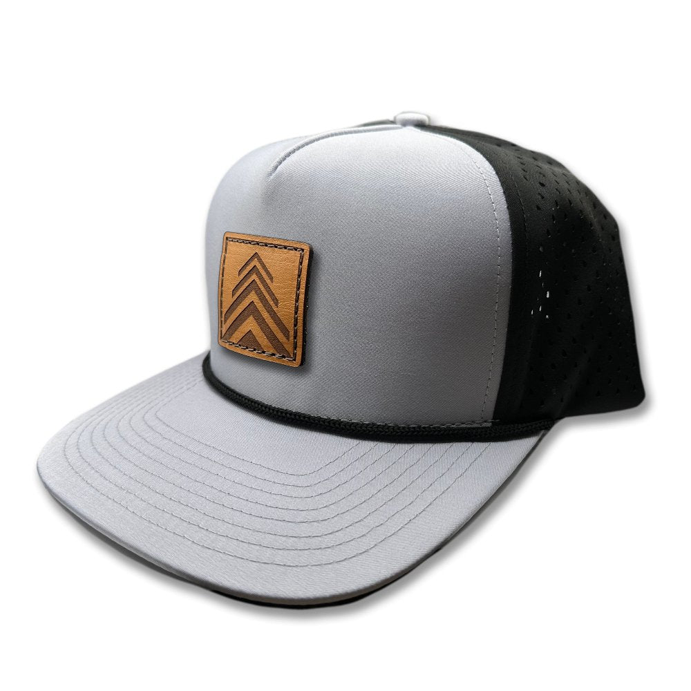 Side view of the Arrow Pine Hat by Outer Wings in grey/black, highlighting the structured high-profile design, classic rope detail, and the distinctive square patch with a modern triple arrow pine tree motif. The hat's water-resistant fabric and adjustable snapback closure make it perfect for exploring the outdoors.