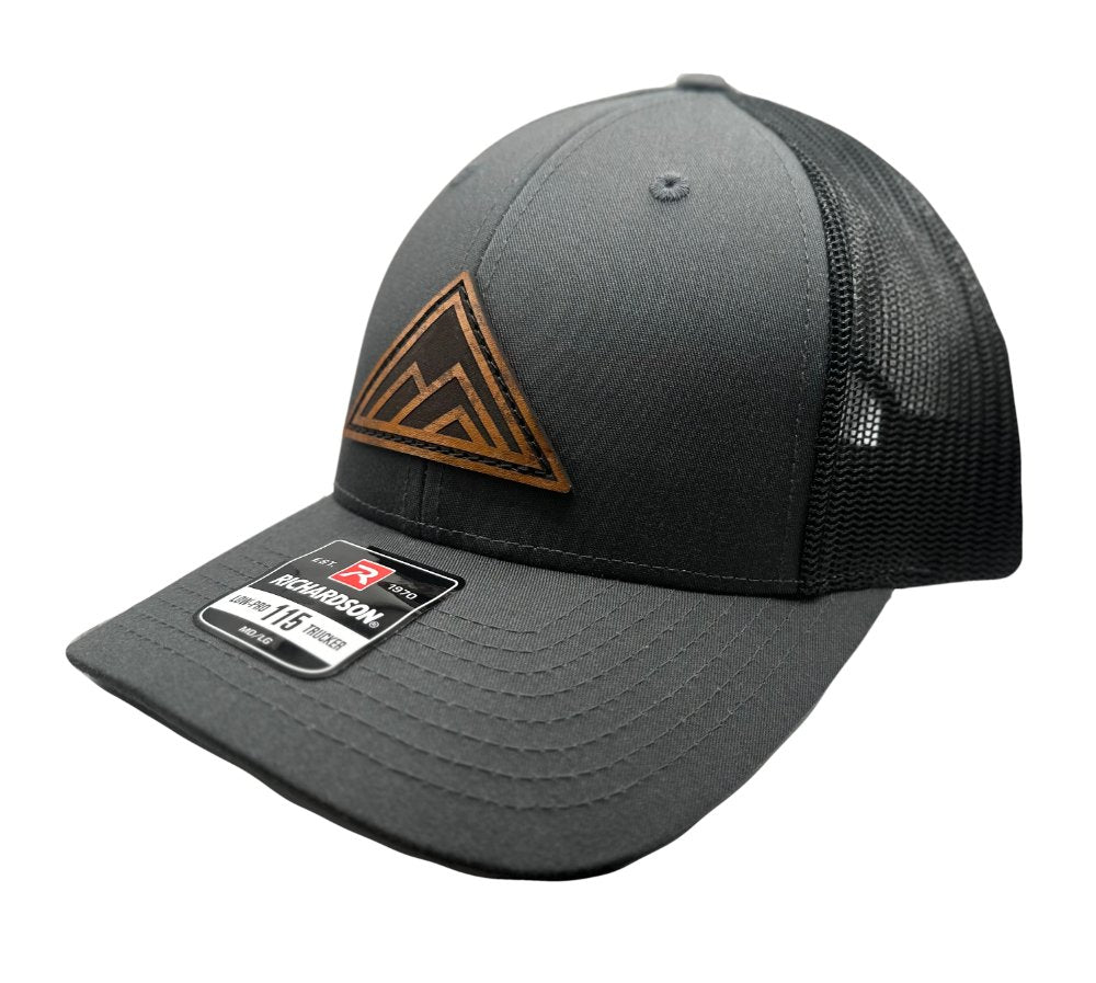 Side view of the Dark Mountain Leather Patch Hat by Outer Wings in charcoal/black on the Richardson 115, showing off the low-profile structured design, adjustable SnapBack closure, and the detailed Dark Mountain leather patch. Perfect for a sleek, stylish look.