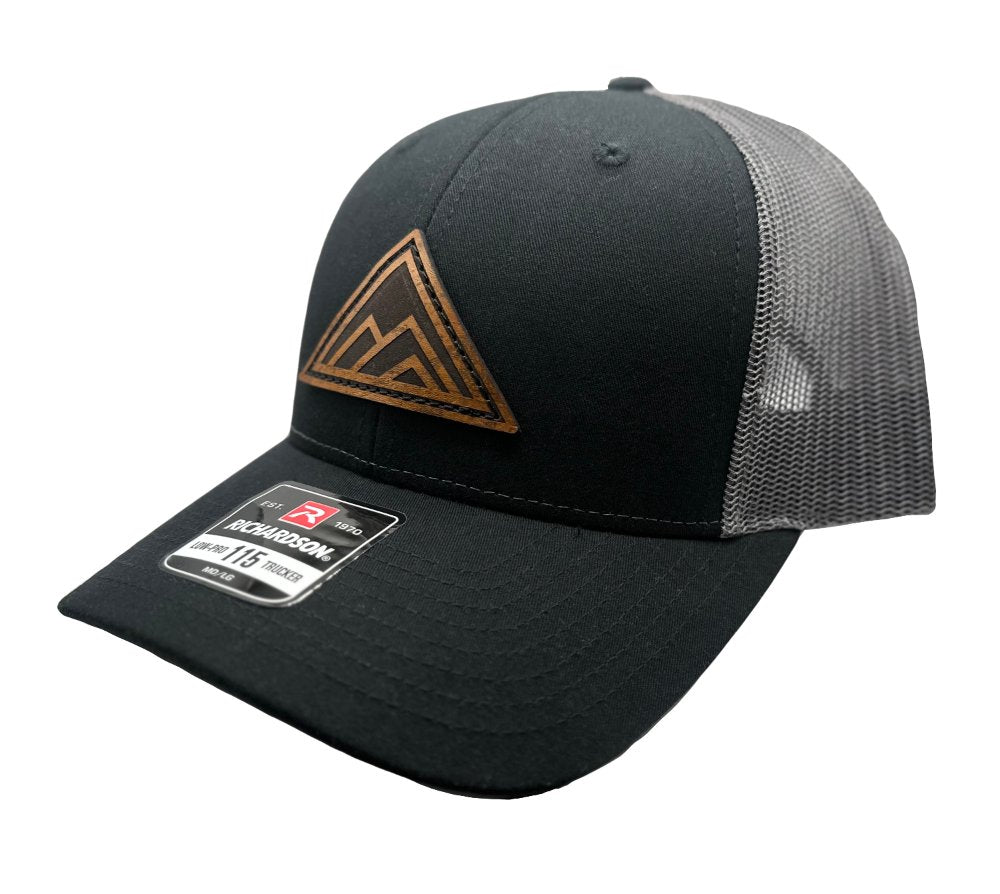 Side view of the Dark Mountain Leather Patch Hat by Outer Wings in black/charcoal on the Richardson 115, showing the structured low-profile fit, adjustable SnapBack, and the distinctive Dark Mountain leather patch. Ideal for those seeking a modern, understated look.