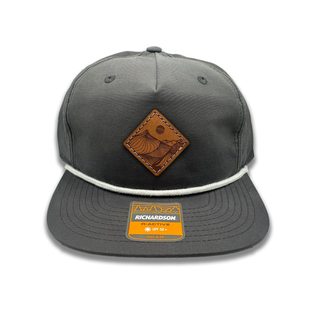 Get a taste of rugged charm with the Charcoal Richardson 256 Rope Umpqua Hat. Made in Colorado, USA, this low profile SnapBack cap features a stylish Desert Mountain patch design. The genuine leather patch, laser engraved and sewn on, adds a touch of sophistication to this flatbill hat crafted from lightweight material.