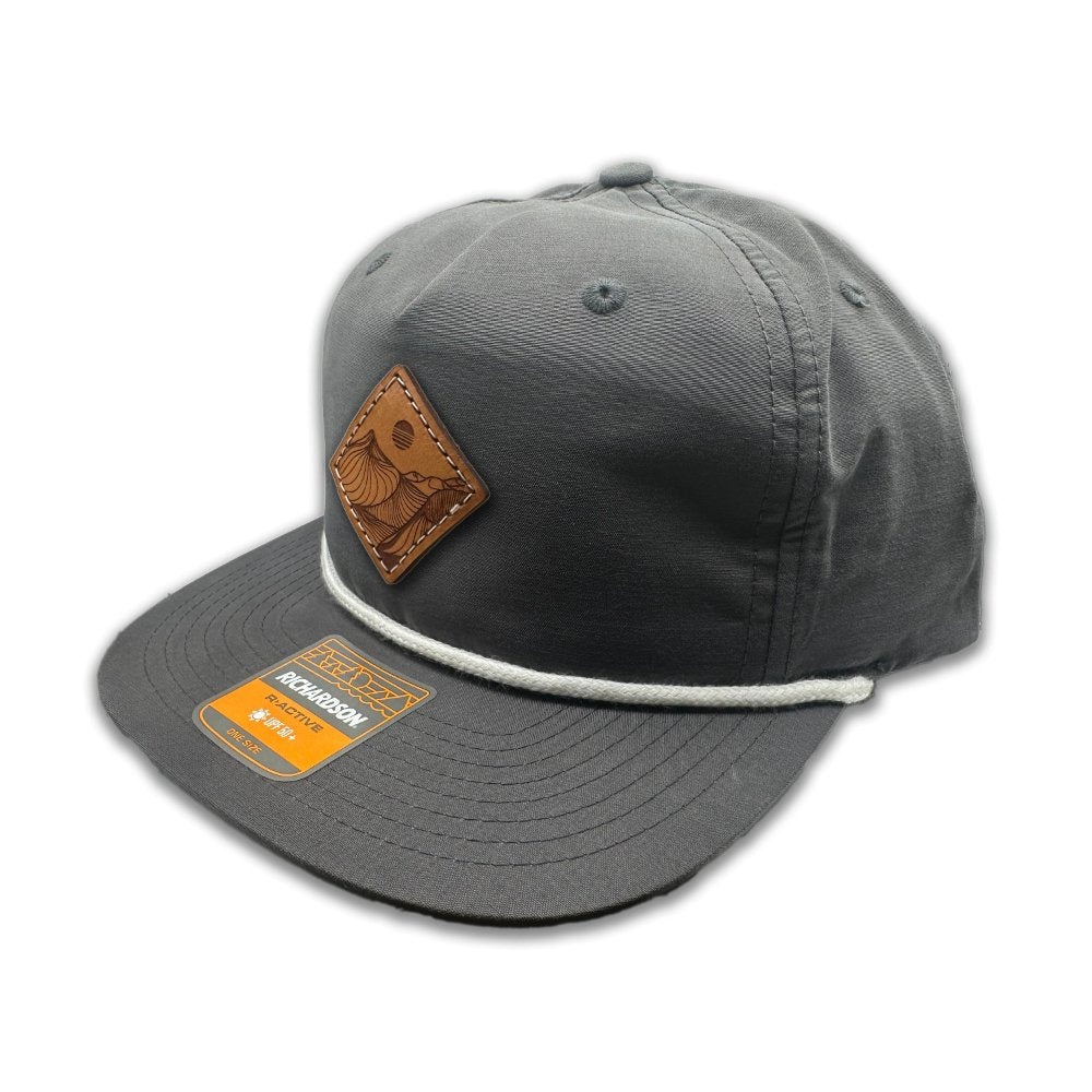 Side view of the Desert Mountain Leather Patch Hat by Outer Wings in charcoal/white on the Richardson 256, highlighting the soft-structured, low-profile fit, breathable mesh support, and the unique Desert Mountain leather patch. The adjustable SnapBack ensures a perfect fit for outdoor enthusiasts