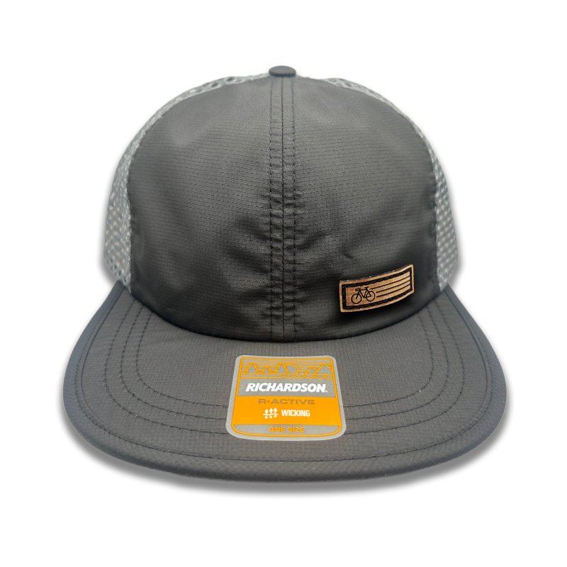 Black Fast Bike Hat by Richardson 935 showcasing the genuine leather Fast Bike patch, laser-engraved and hand-sewn, on a black polyester trucker hat with charcoal accents.