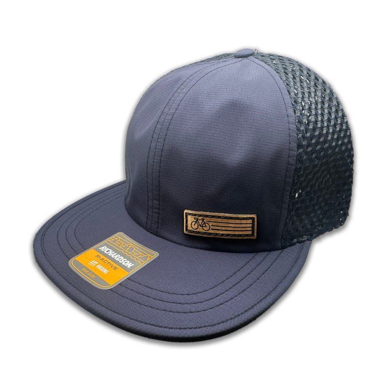 Side view of the Navy Fast Bike Hat, featuring the matching navy wide-set mesh back and adjustable quick-adjust pack webbing, with the Fast Bike leather patch visible from the side.