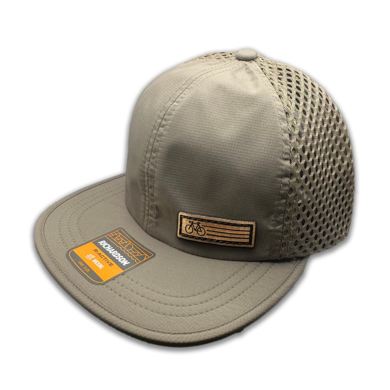 Side view of the Khaki Fast Bike Hat, showing the wide-set mesh back and adjustable quick-adjust pack webbing, with the Fast Bike leather patch visible from the side.