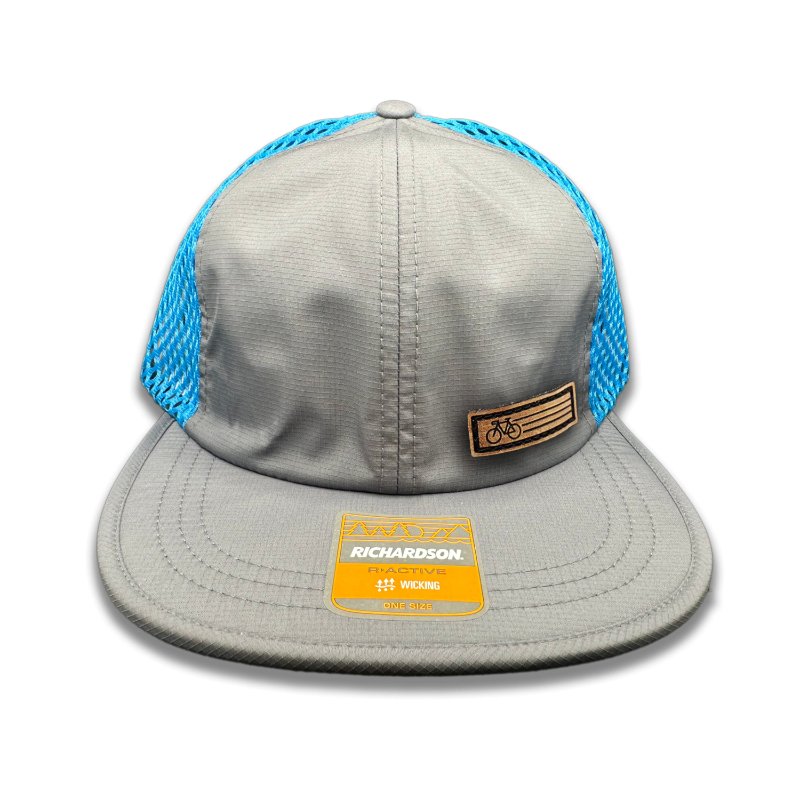 Charcoal Fast Bike Hat by Richardson 935 showcasing the genuine leather Fast Bike patch, laser-engraved and hand-sewn, on a charcoal-colored polyester trucker hat with cyan accents.