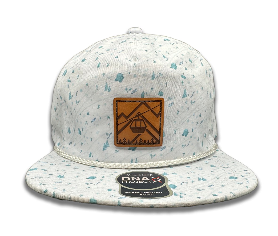 Front view of the Gondola Hat in Mountain Blue by Outer Wings, featuring a hand-sewn genuine leather patch with winter-themed designs of skiers, ski lifts, snow cats, and pine trees on an Imperial Umpqua rope hat. The hat has a mid-profile, structured five-panel design with a moisture-wicking sweatband and adjustable leather strap