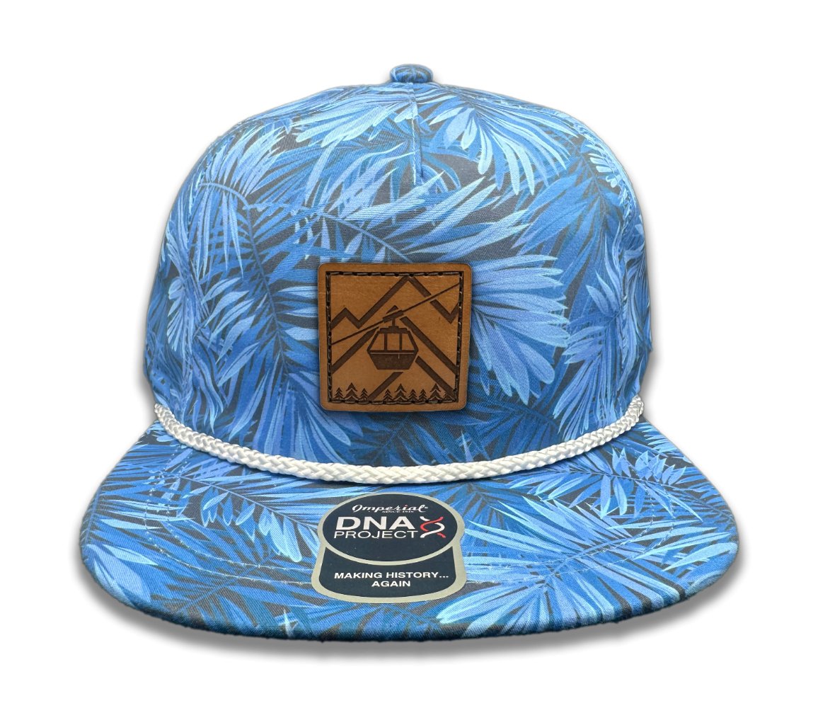 Front view of the Gondola Hat in Blue Pine by Outer Wings, displaying a genuine leather patch with detailed winter-themed designs including skiers, ski lifts, and pine trees. Crafted on an Imperial Umpqua rope hat with a structured mid-profile, moisture-wicking sweatband, and adjustable leather strap