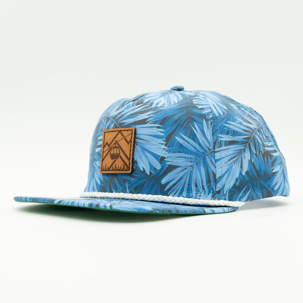 Side view of the Gondola Hat in Blue Pine, highlighting the structured design, adjustable leather strap, and classic rope detail. The hat features a hand-sewn leather patch with winter motifs, making it an ideal accessory for snowy adventures.