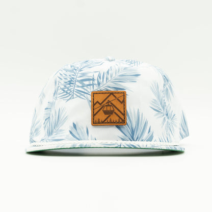 Front view of the Gondola Hat in White Pine by Outer Wings, featuring a hand-sewn genuine leather patch with winter-themed designs like skiers and ski lifts. Built on an Imperial Umpqua rope hat, it includes a structured five-panel design, mid-profile, and a moisture-wicking sweatband.