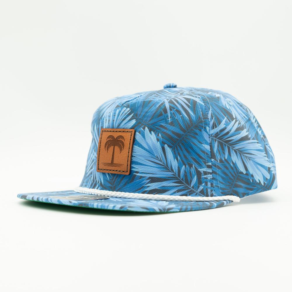 A blue and white tropical palm leaf patterned snapback cap with a brown leather patch featuring a palm tree logo on the front, set against a plain white background.

Color: Blue Hawaiian