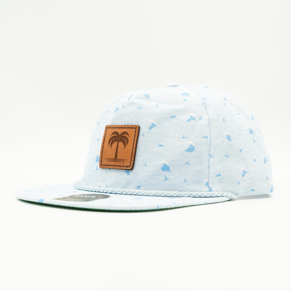 A light blue and white patterned snapback cap with a brown leather patch featuring an embossed palm tree logo on the front, set against a plain white background.

Color: Blue Wave