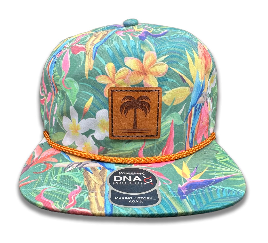 Front view of the Island Breeze Hat in Hawaiian Rainforest by Outer Wings, featuring a hand-sewn, genuine full-grain leather patch with a palm tree engraving. The hat showcases a vibrant rainforest-themed print on the Imperial DNA010 Aloha Rope Hat, with a structured five-panel, mid-profile design and an adjustable leather strap.