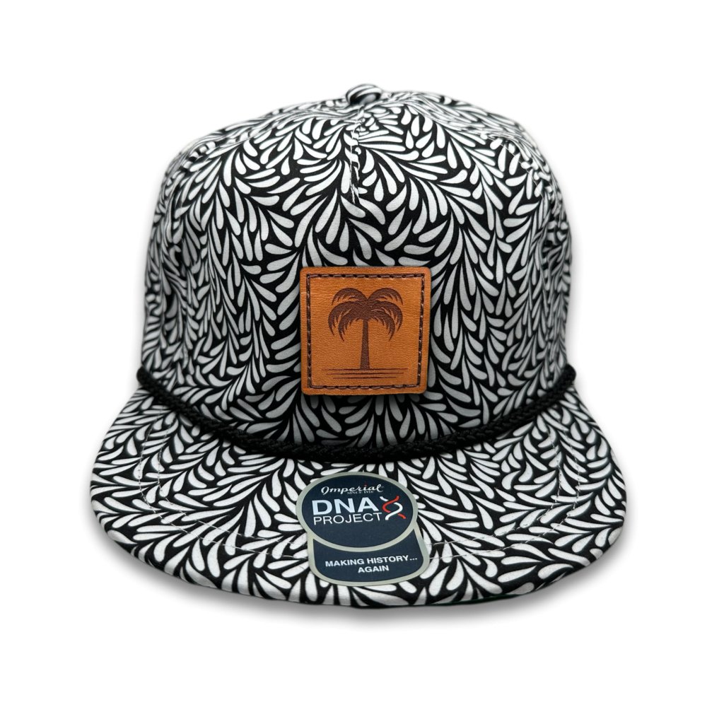 Front view of the Island Breeze Hat in Throwback Black by Outer Wings, showcasing a hand-sewn leather patch with a palm tree engraving. The Imperial DNA010 Aloha Rope Hat features a classic black print with a structured five-panel, mid-profile design and a moisture-wicking sweatband for comfort.