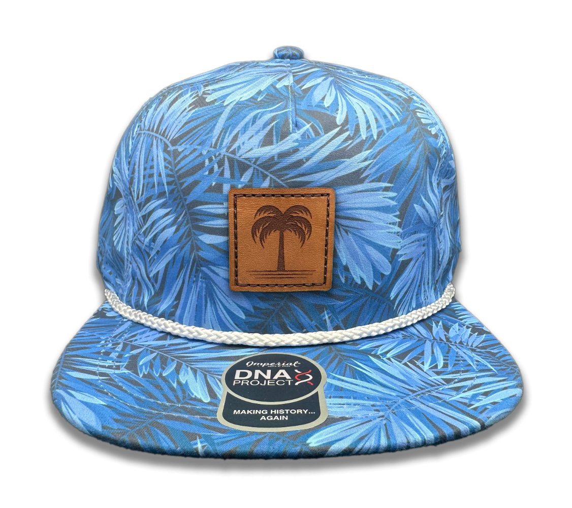 Front view of the Island Breeze Hat in Blue Hawaiian by Outer Wings, displaying a hand-sewn leather patch with a palm tree engraving. This hat features a blue Hawaiian-themed print on the Imperial DNA010 Aloha Rope Hat, combining style and comfort with its structured five-panel, mid-profile design and moisture-wicking sweatband.