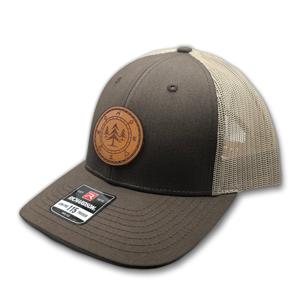 Side view of the Lost Pine Hat in Brown/Khaki, showcasing the hat’s structured design, breathable mesh back, and classic pre-curved visor. The leather patch is hand-stitched and features a compass and pine trees design, adding a touch of wilderness to your style.