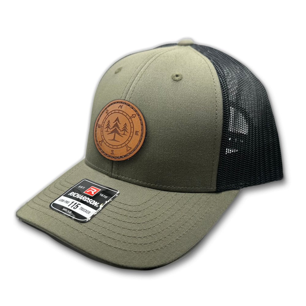 Side view of the Lost Pine Hat in Loden/Black, highlighting the hat’s breathable mesh back, structured profile, and adjustable closure. The hat includes a hand-stitched leather patch with a compass and pine trees design, ideal for nature lovers.