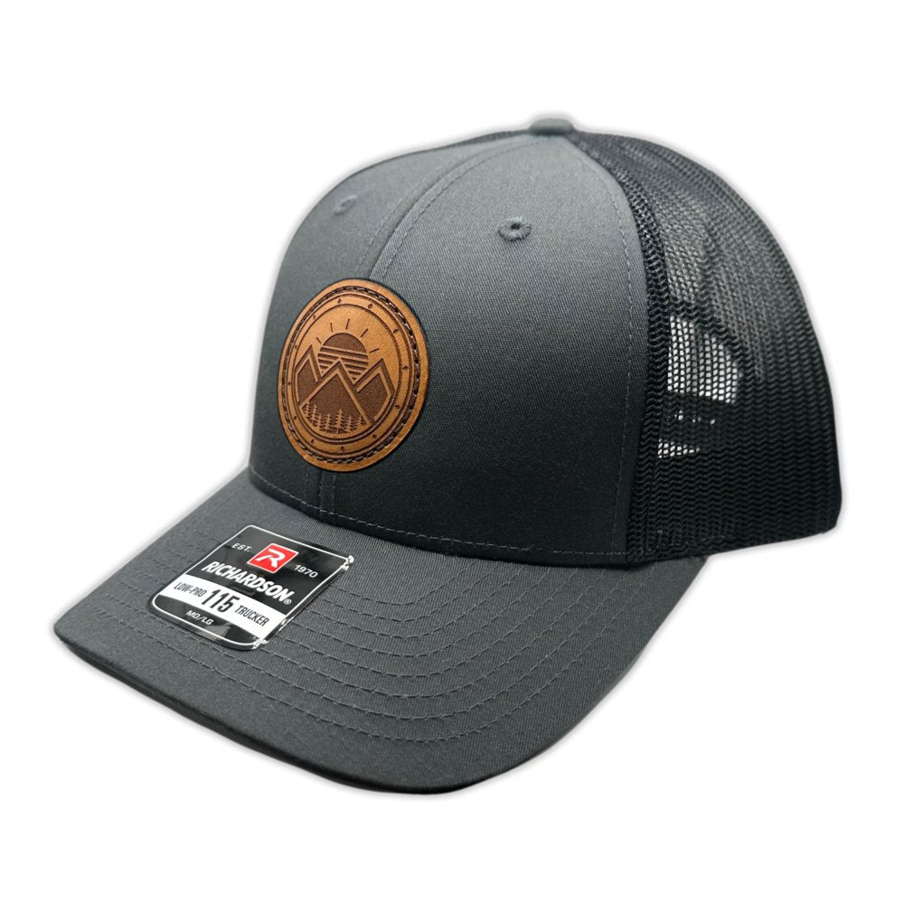 Side view of the Modern Mountains Leather Patch Hat in Charcoal/Black, highlighting the structured low-profile design, breathable mesh back, and classic pre-curved visor. The hat includes a hand-sewn leather patch with a modern mountains and sunset design, adding a touch of outdoor style.