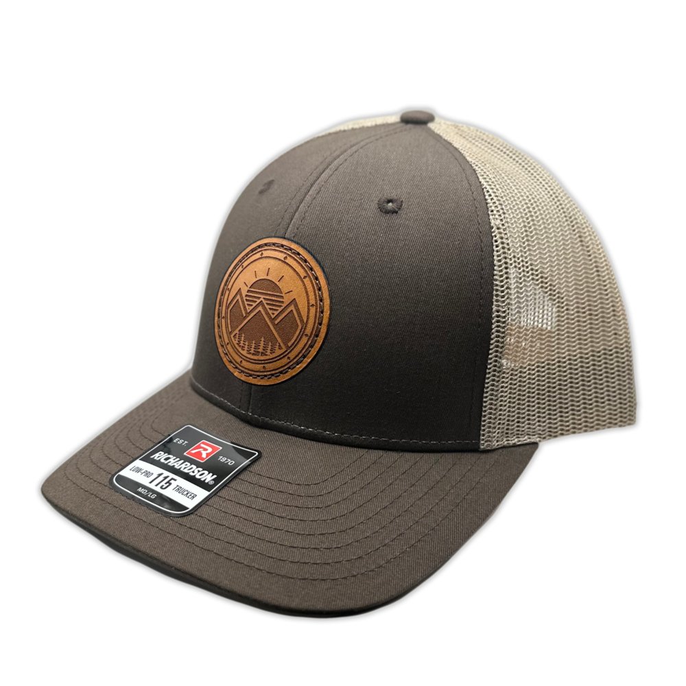 Side view of the Modern Mountains Leather Patch Hat in Brown/Khaki, highlighting the structured profile, breathable mesh back, and adjustable SnapBack closure. The genuine leather patch with a modern mountains and sunset design adds a distinctive touch to the hat’s style.