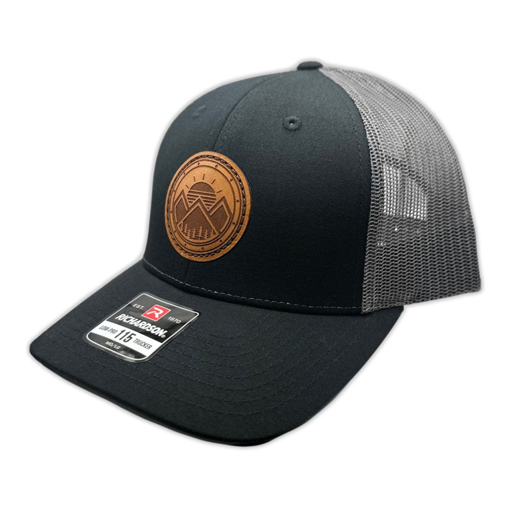 Side view of the Modern Mountains Leather Patch Hat in Black/Charcoal, highlighting the structured profile, breathable mesh back, and adjustable SnapBack closure. The genuine leather patch with modern mountains and sunset design is hand-sewn for added durability and style.