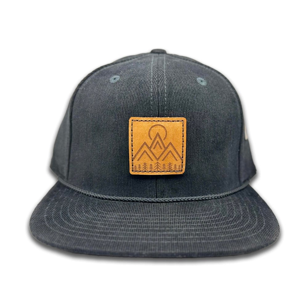 Front view of the Moonlite Mountain Hat in black by Outer Wings, featuring a square leather patch with a laser-engraved design of mountains, pine trees, and a moon. The Richardson 253 hat is made from 100% cotton corduroy with a high-profile, six-panel build, flat bill, and adjustable snapback for a perfect fit.