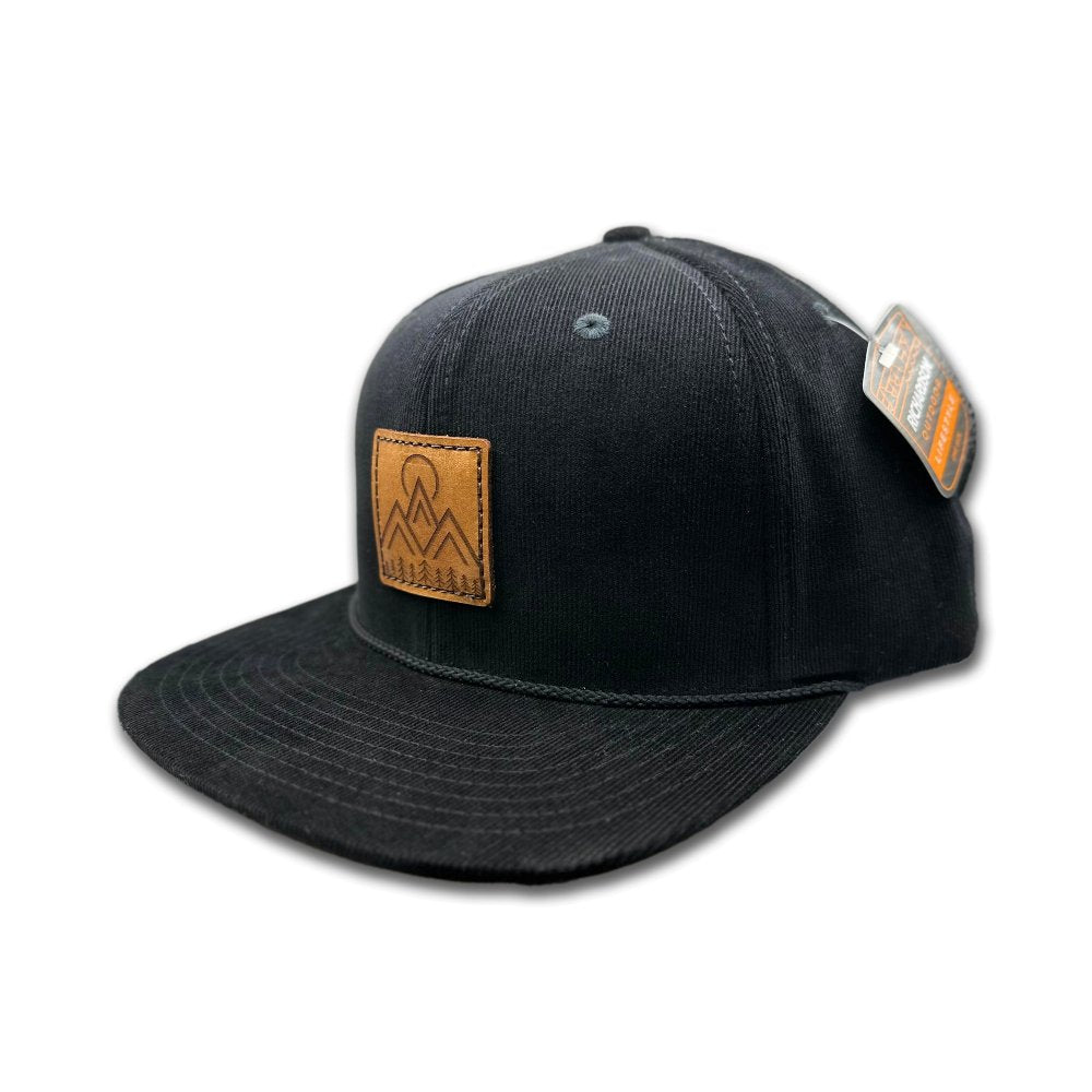 Side view of the Moonlite Mountain Hat in black, highlighting the structured high-profile, six-panel design and adjustable snapback closure. The hat features a genuine leather patch with an engraved design of mountains, pine trees, and a moon, capturing the essence of outdoor adventures.