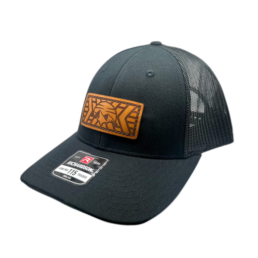 Side view of the Mosaic Mountain Leather Patch Hat by Outer Wings in black/black, highlighting the structured design of the low profile Richardson 115 hat. The unique leather patch showcases a modern mountain and sunset design, making it a standout piece among custom leather patch hats, perfect for outdoor adventures.