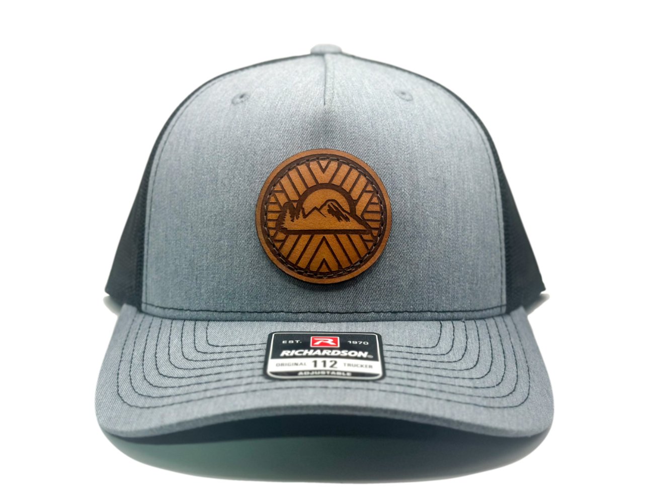 Front view of the Mosaic Sunset Leather Patch Hat by Outer Wings in heather/black, crafted on the Richardson 112FP trucker hat. This custom leather patch hat features a laser-engraved Mosaic Sunset design on a full-grain leather patch, hand-sewn onto the seamless front panel. The hat offers a breathable mesh back and an adjustable Snap-Back closure for a comfortable fit, ideal for outdoor enthusiasts.