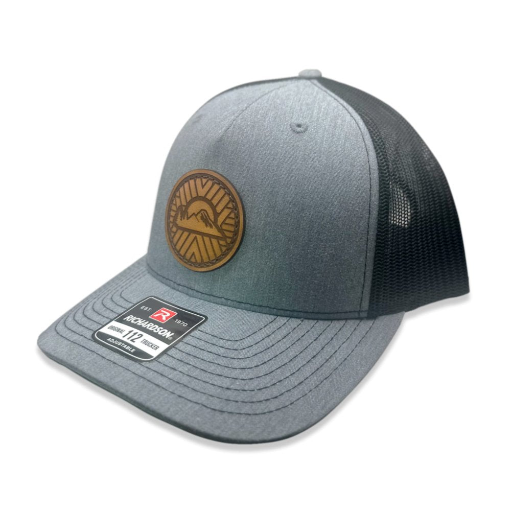 Side view of the Mosaic Sunset Leather Patch Hat by Outer Wings in heather/black, highlighting the structured mid-profile design of the Richardson 112FP. The laser-engraved leather patch with the Mosaic Sunset design adds a unique touch to this custom leather patch hat, perfect for hiking, casual outings, or everyday wear. The breathable mesh back and adjustable Snap-Back closure enhance comfort and style.