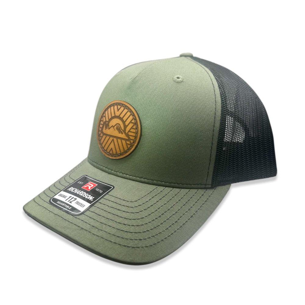 Side view of the Mosaic Sunset Leather Patch Hat by Outer Wings in loden/black, highlighting the structured mid-profile design of the Richardson 112FP. The side showcases the unique laser-engraved leather patch with the Mosaic Sunset design, adding a distinctive look to this custom leather patch hat. Ideal for outdoor adventures, the hat features a breathable mesh back and adjustable Snap-Back for comfort and versatility.