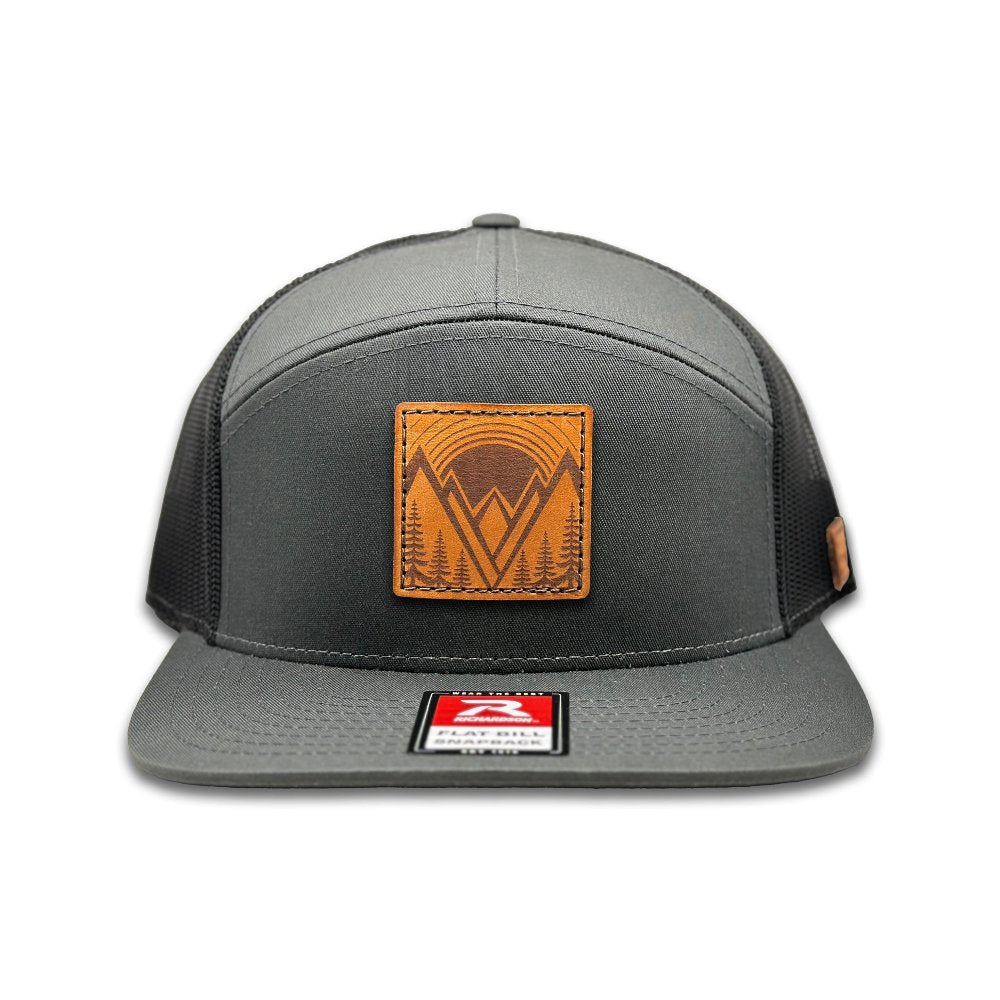 Front view of the Richardson 168 Flat Bill Trucker Hat in charcoal/black, showcasing the high-profile, seven-panel structure. The hat combines a cotton/nylon/polyester blend front with a mesh back and flat bill, offering a stylish and adjustable fit for outdoor activities and casual wear.