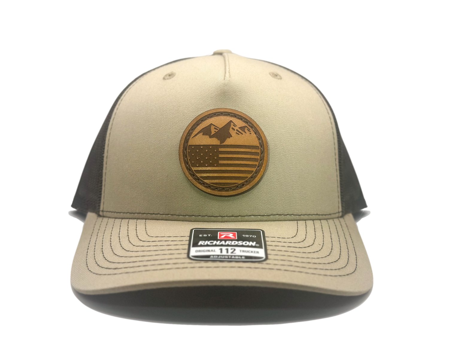 Front view of the Mountain Flag leather patch hat on Richardson 112FP in Khaki/Coffee, featuring a five-panel, mid-profile design with a real leather patch of mountains and the American flag. Ideal for mountain man apparel lovers