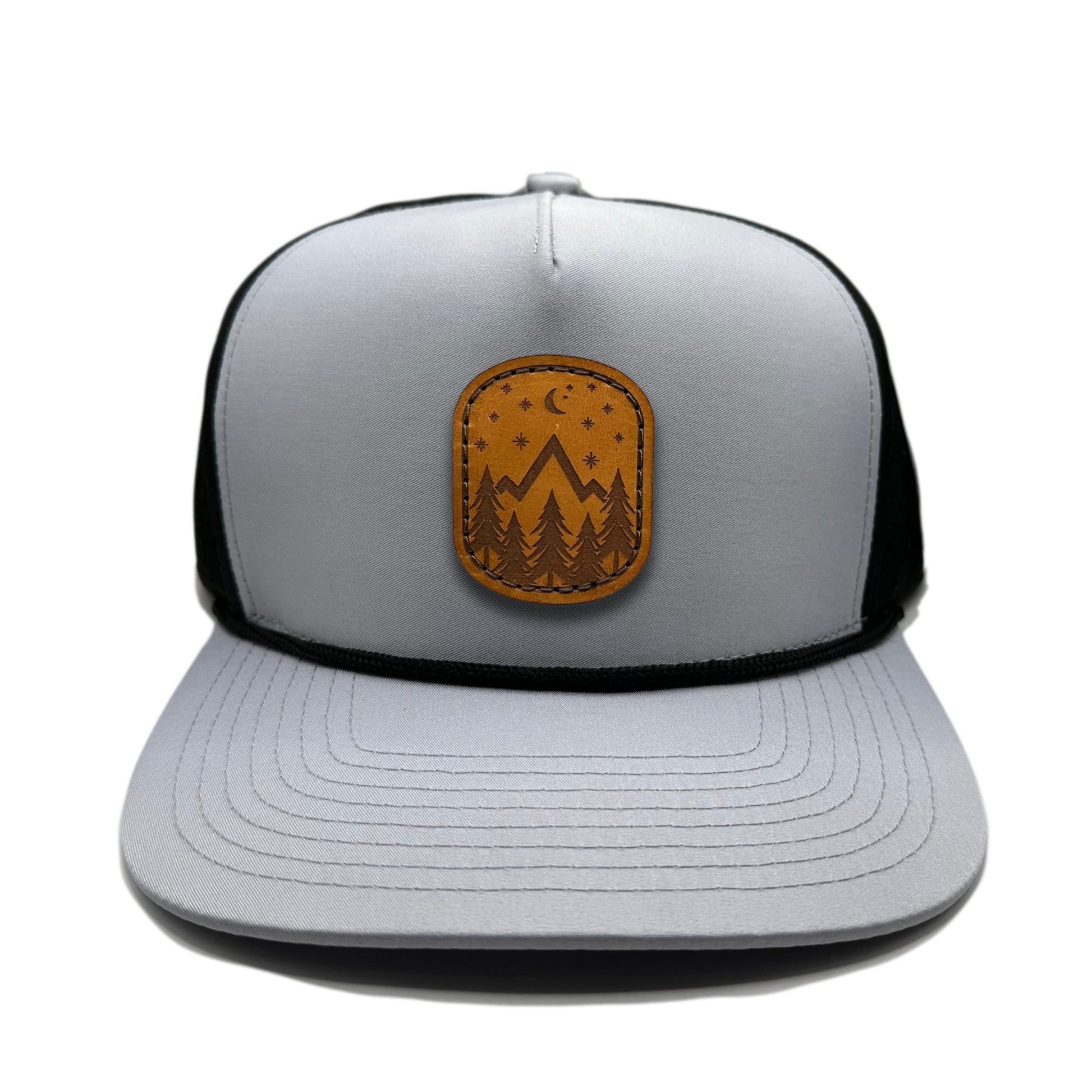 Front view of the Starry Night Leather Patch Hat by Outer Wings in Grey/Black, featuring a high-profile, structured Outer Wings 970 rope trucker hat with a laser-engraved leather patch showcasing mountains, pine trees, stars, and a half moon. Ideal for outdoor activities.