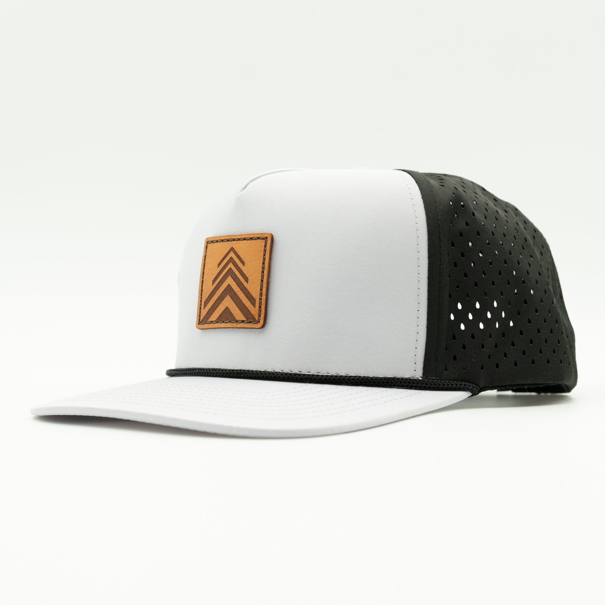 A white and black trucker-style cap with a brown leather patch on the front featuring a chevron design, photographed on a clean white 
background.

Color: Grey/Black
