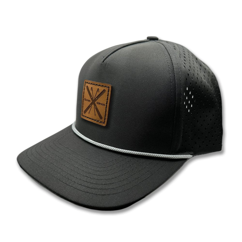 Side view of the Alpine Wings Hat by Outer Wings in black, showing the hat's structured profile, classic rope detail, and square patch with crossed skis and 'Outer Wings.' This high-profile hat offers durability and comfort, with water-resistant fabric and an adjustable snapback closure.