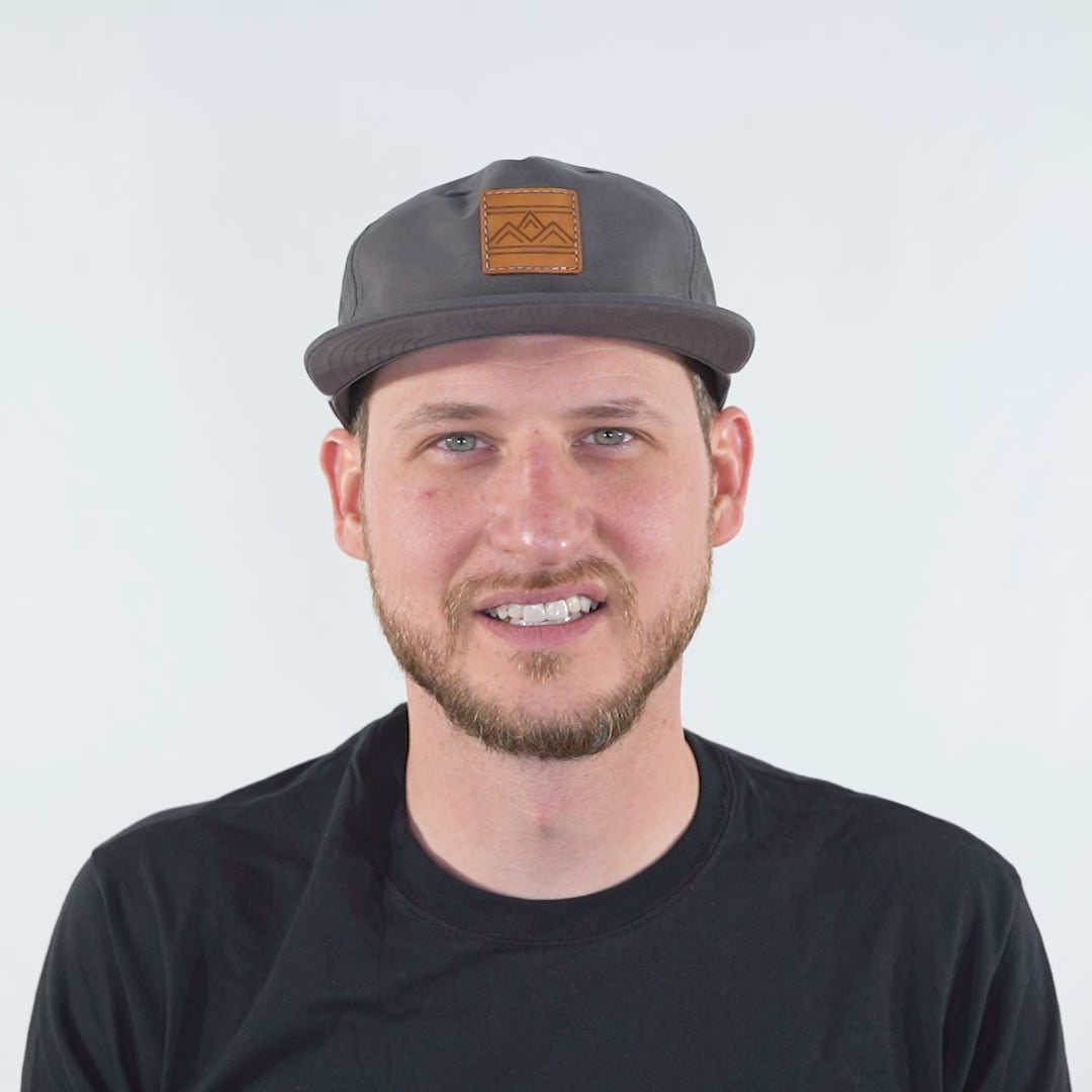 Man wearing Rustic Ridge charcoal and white Richardson 256 rope hat, turning to show mesh back, rope detail, and low profile fit.
Color: Charcoal/White