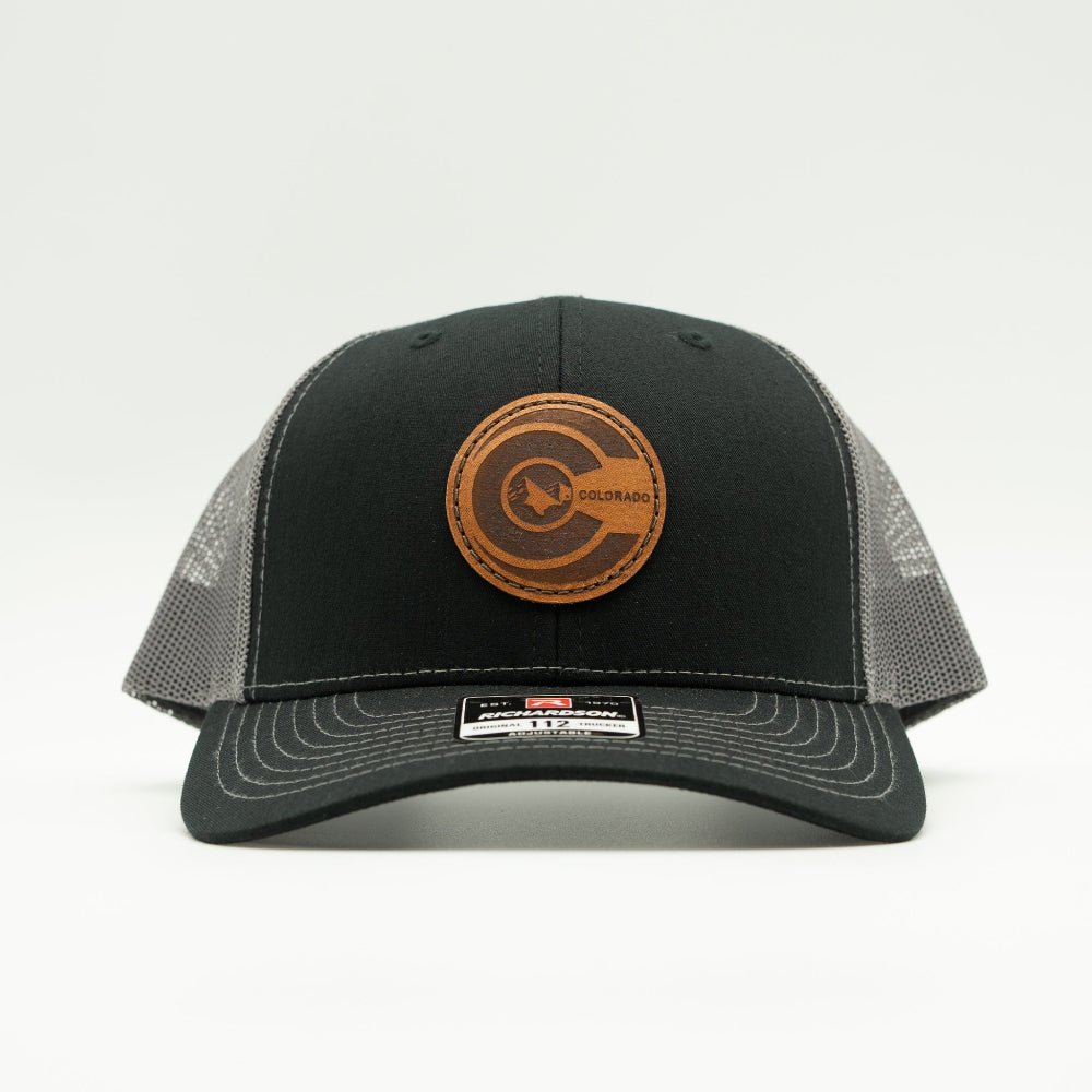 Front view of black and charcoal Richardson 112 trucker hat featuring round veg-tan leather Colorado flag patch and structured crown.

Color: Black/Charcoal