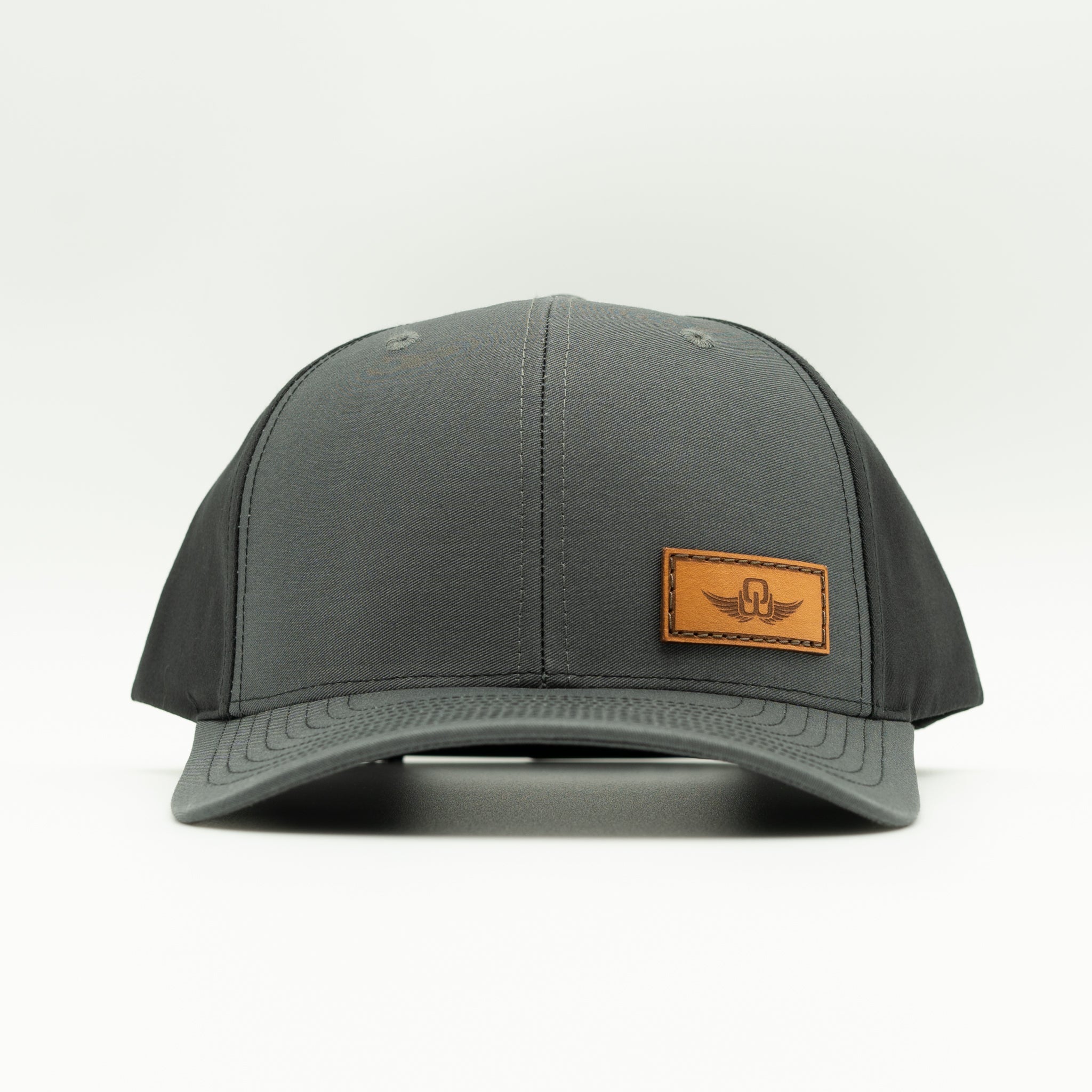 Front view of charcoal/black Richardson 312 full-fabric hat with sewn Spread Your Wings leather patch and curved bill.