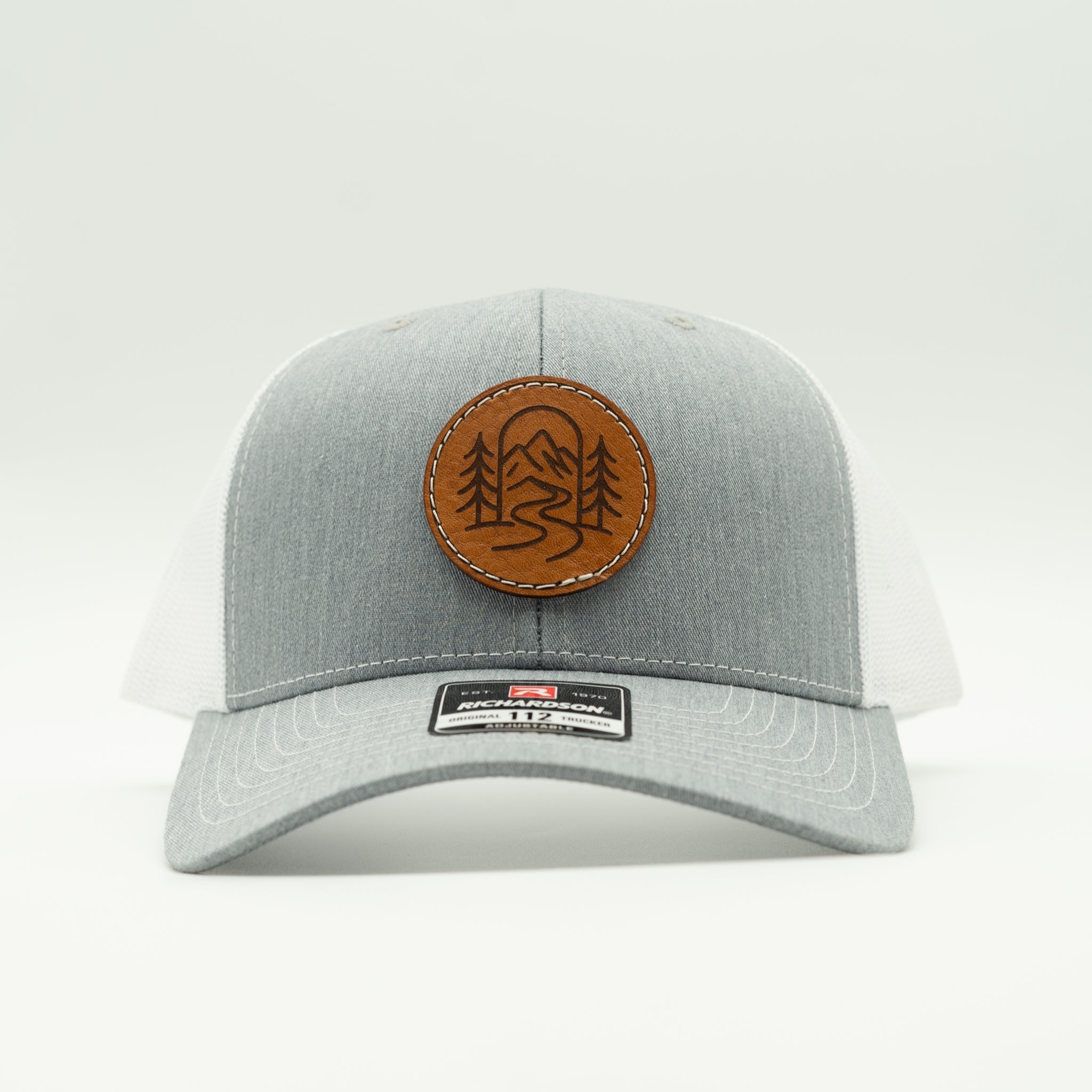 Front view of heather grey and white Richardson 112 The Passage hat with round veg tan leather mountain trail patch.