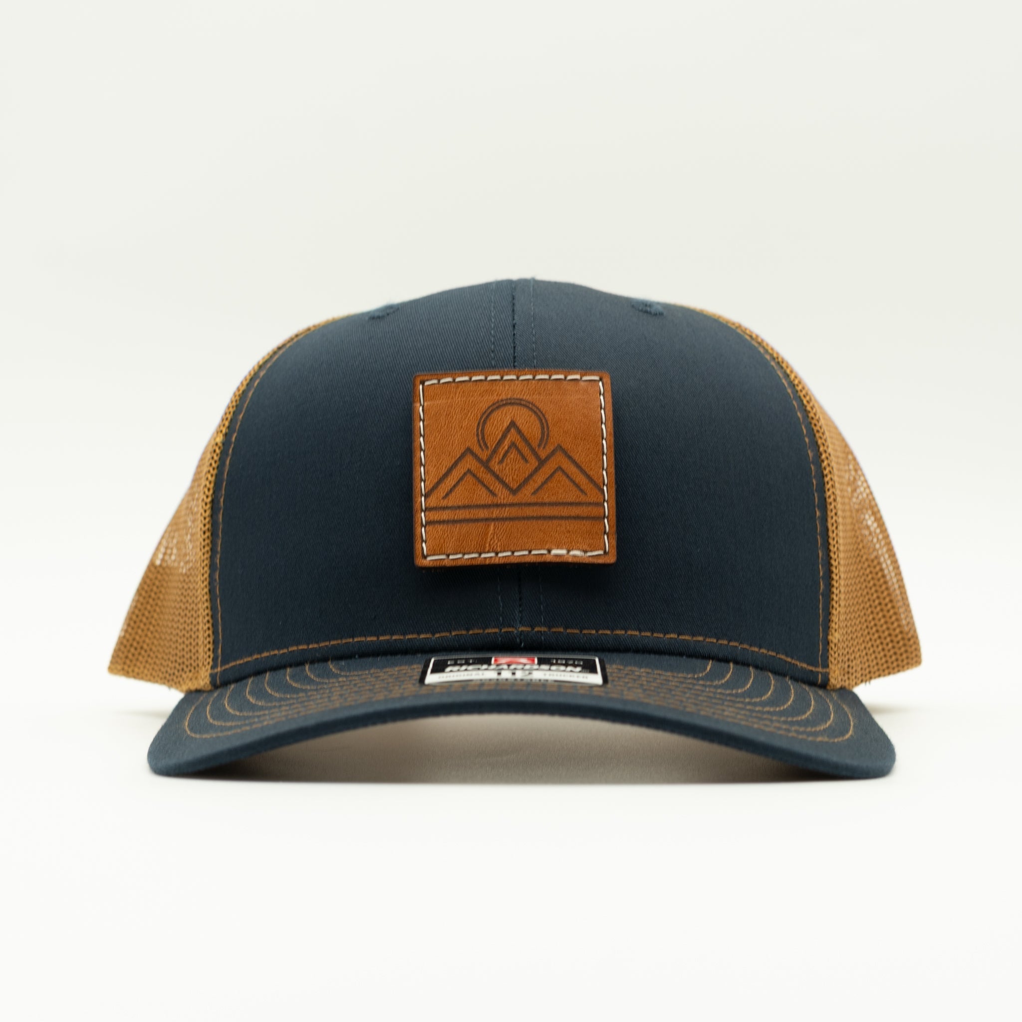 Front view of Lunar Ridge navy and caramel Richardson 112 trucker hat with veg tan leather mountain patch

Color: Navy/Caramel