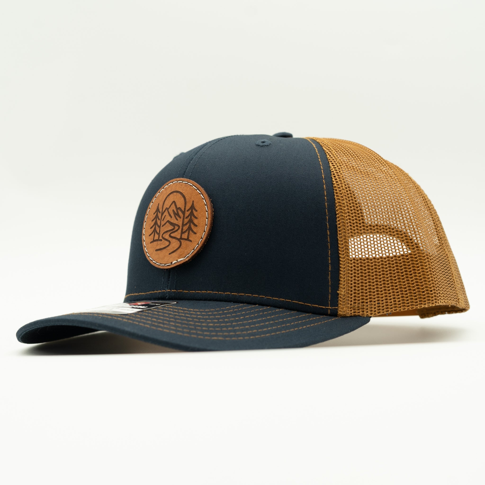 Side view of The Passage navy and caramel Richardson 112 leather patch outdoor trucker hat.