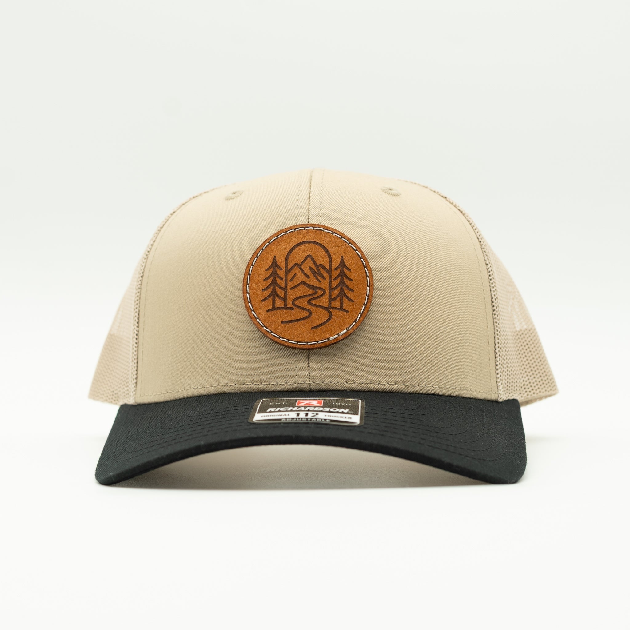 Front view of khaki and black Richardson 112 The Passage trucker with round engraved leather patch.