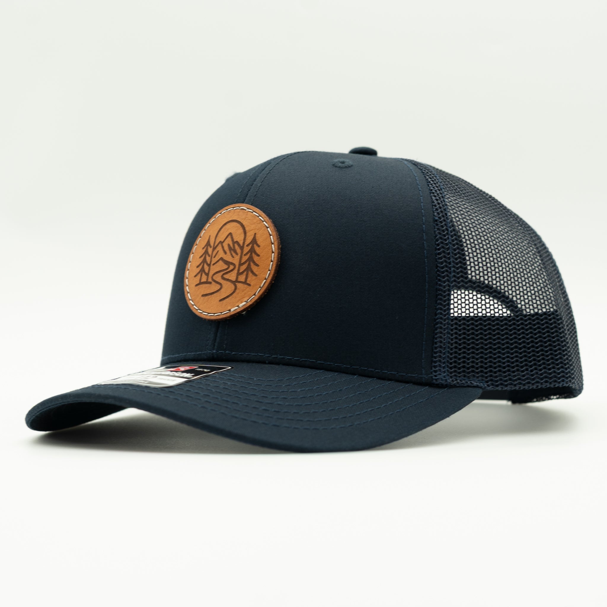 Side view of The Passage solid navy Richardson 112 leather patch mountain trucker hat.