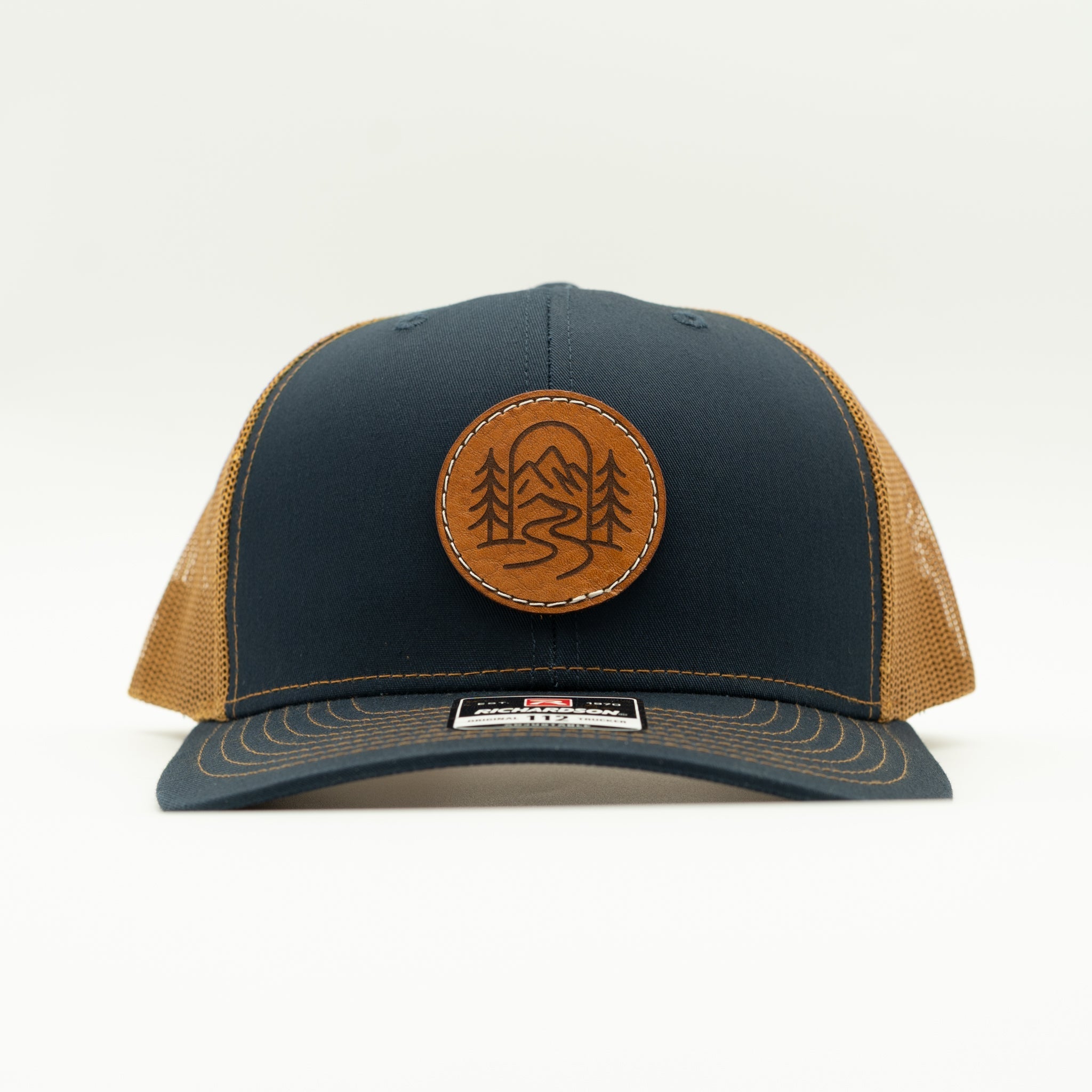 Front view of navy and caramel Richardson 112 The Passage hat with round mountain leather patch.