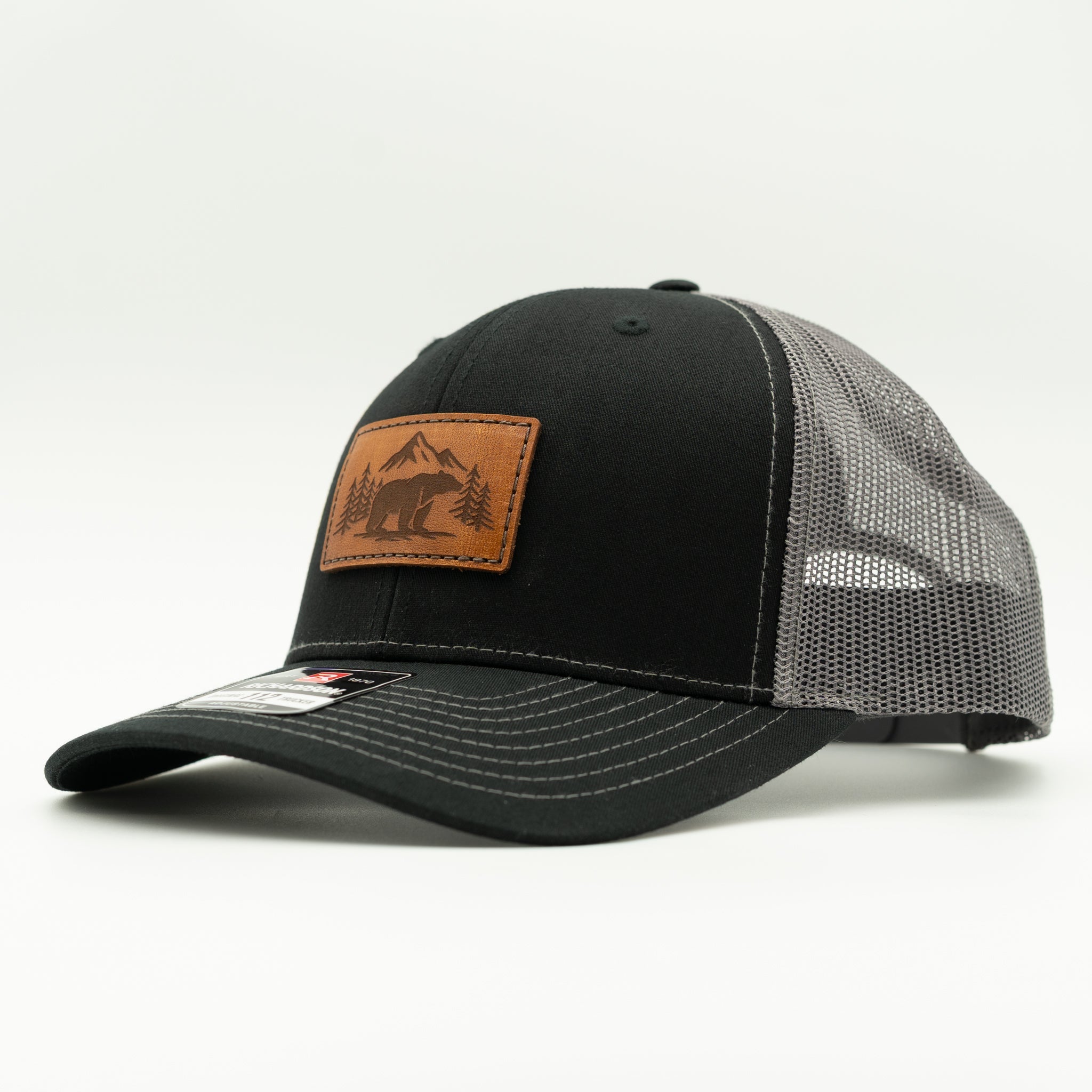 Side view of Bearline Peak leather patch hat on black and charcoal Richardson 112, highlighting engraved bear and pine tree patch, curved visor, and breathable mesh back.

Color: Black/Charcoal