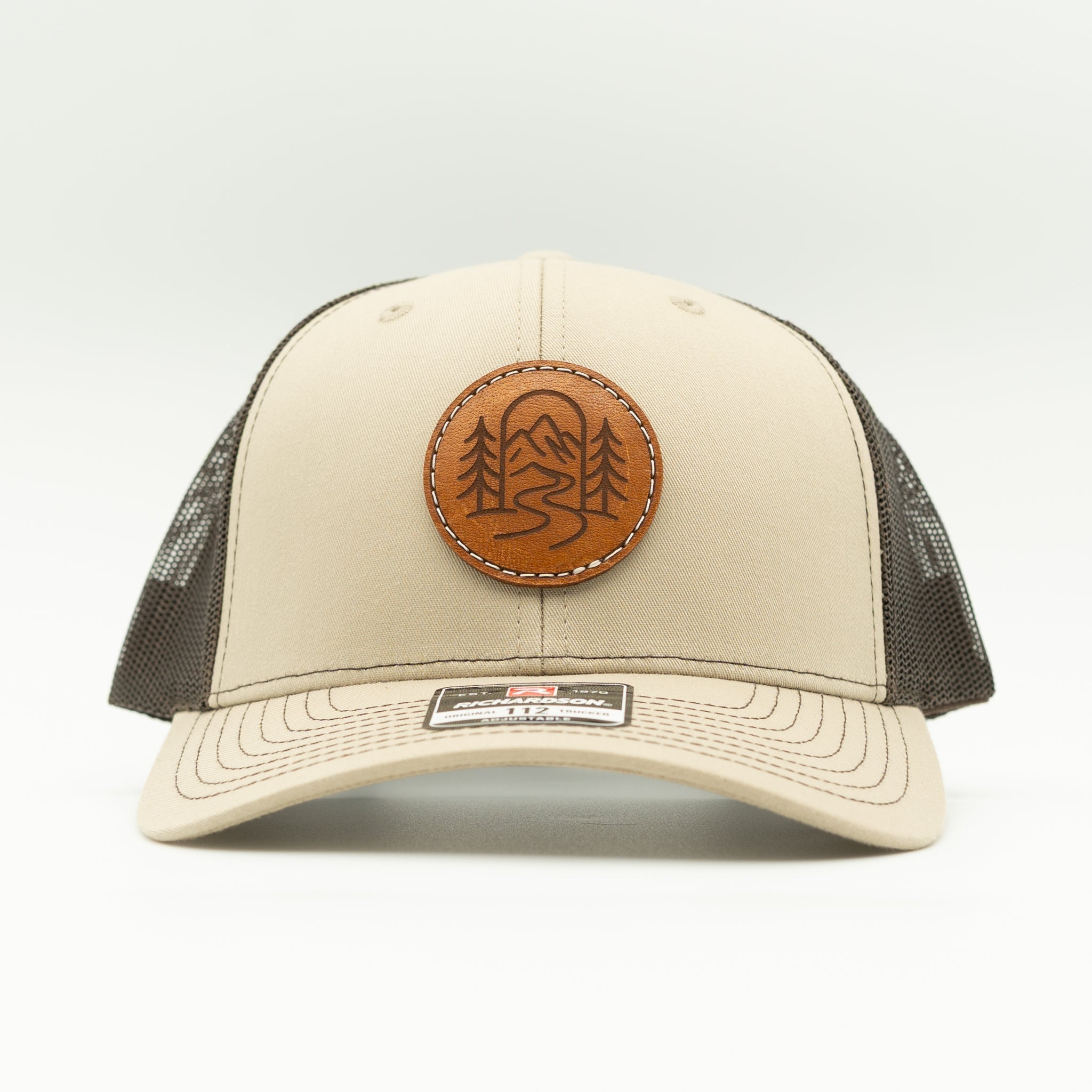 Front view of khaki and coffee Richardson 112 The Passage trucker with round engraved leather patch.