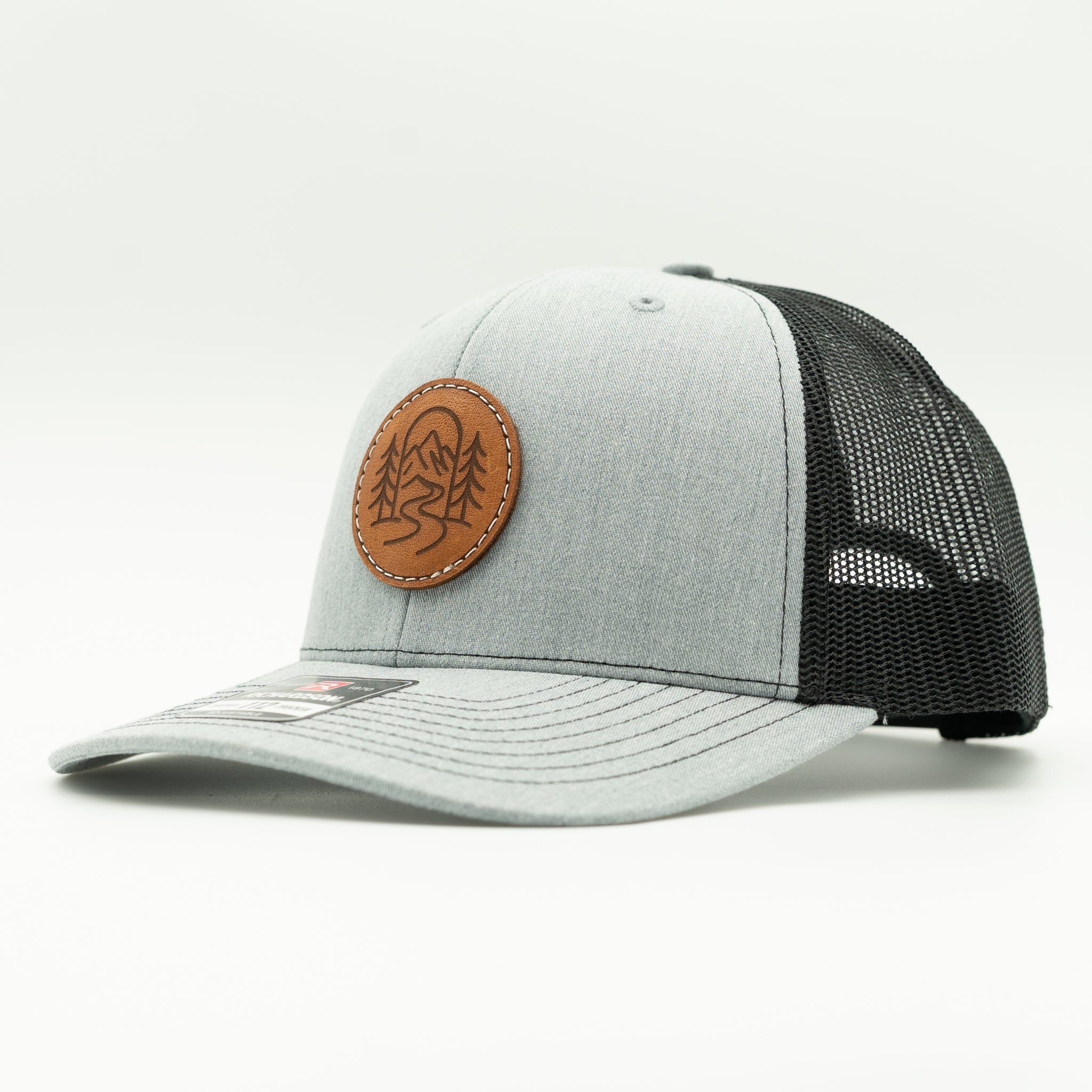 Side view of The Passage heather grey and black Richardson 112 leather patch trucker hat.