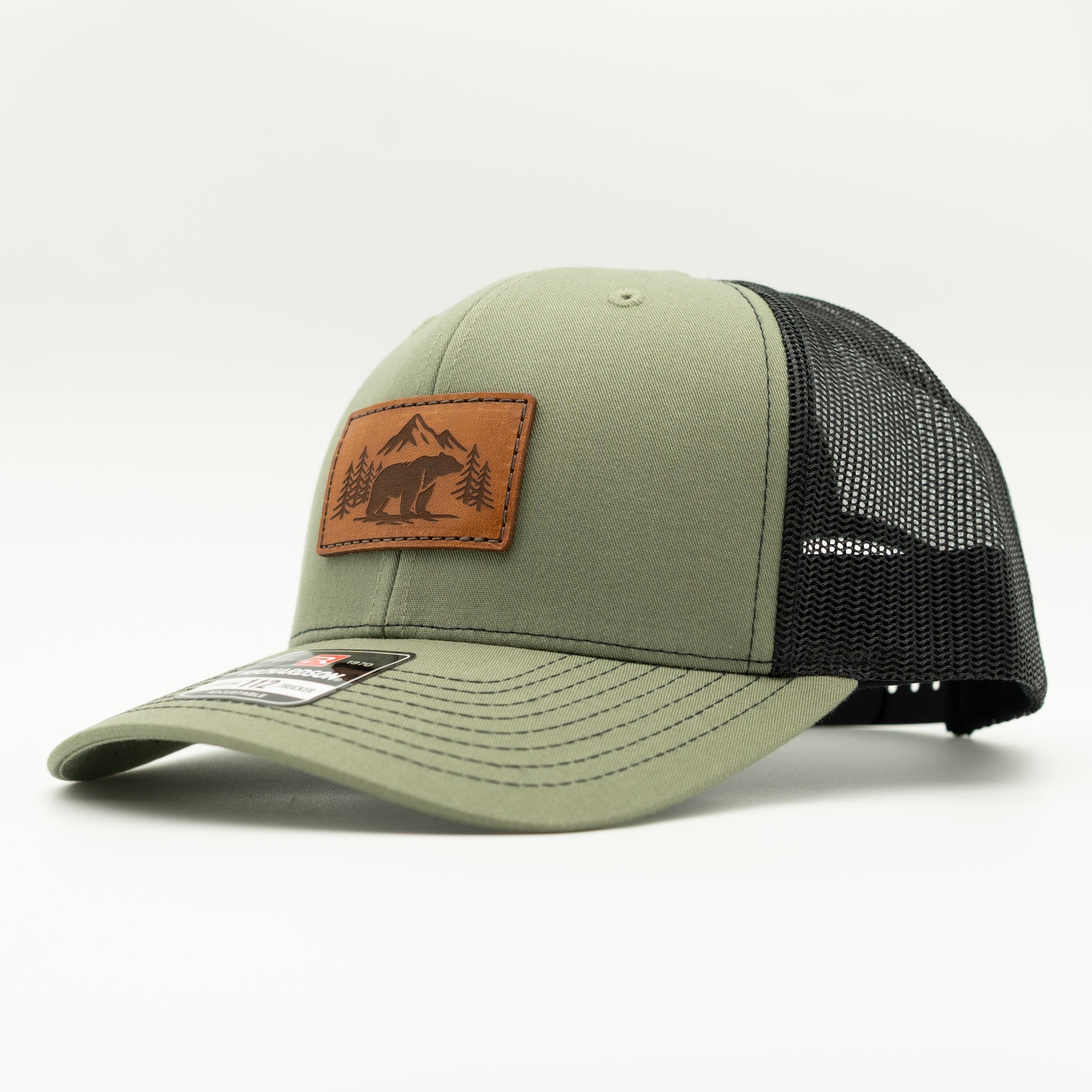 Side view of Bearline Peak leather patch hat on loden and black Richardson 112, showing light brown leather patch, curved visor, and mesh back for breathable mountain wear.

Color: Loden/Black