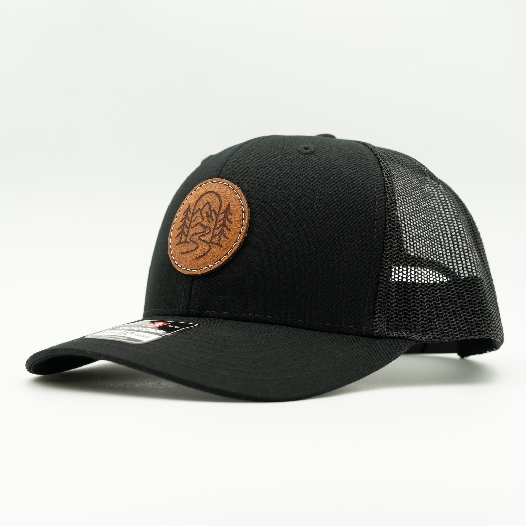Side view of The Passage solid black Richardson 112 leather patch mountain hat with mesh back.